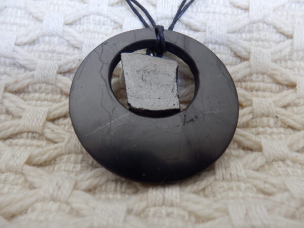 a black stone necklace on a white knitted surface 2