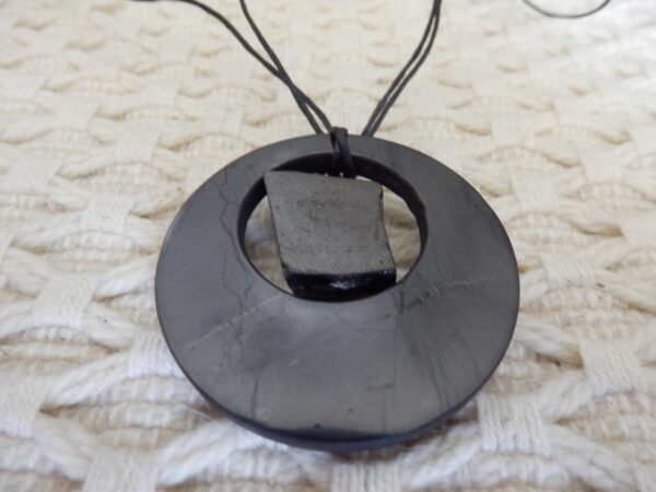 a black stone necklace on a white knitted surface
